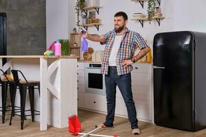 a man with a beard in the kitchen decided to take a break and fooling around with a sprinkler in his hands photo