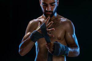 Boxer preparando su guantes para un luchar. foto de muscular hombre fornido arriba manos en negro antecedentes.