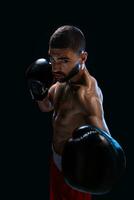 Man is hitting an opponent. Focused fighter with naked torso and boxing gloves looking at the camera. Win. photo