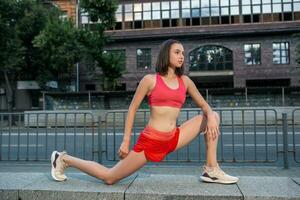 deportivo mujer extensión y calentamiento arriba piernas antes de corriendo urbano aptitud ejercicio. deporte y sano estilo de vida concepto. foto