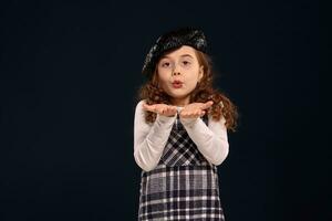 Stylish brunette kid is posing in studio on a black background. Children's fashion. photo