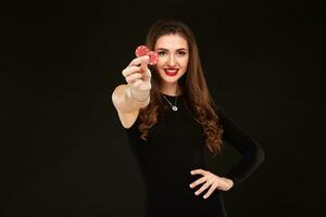 Sexy curly hair brunette posing with chips in her hands, poker concept black background photo