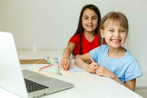 Two cute little sisters study together at home. Education for kids. photo