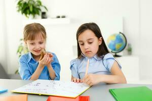 bonito elegante colegialas estudiando durante su en línea lección a hogar, social distancia durante cuarentena, autoaislamiento, en línea educación concepto foto