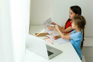 Pretty stylish schoolgirls studying math during her online lesson at home, social distance during quarantine, self-isolation, online education concept photo