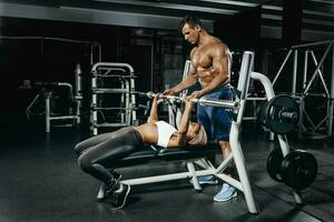 Fitness instructor exercising with his client at the gym. photo