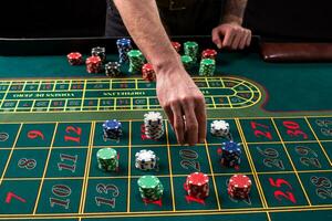 A close-up vibrant image of green casino table with roulette, with the hands of croupier and multicolored chips. photo