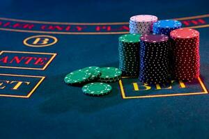 Colorful chips piles, some of them are laying nearby on a blue cover of a playing table. Gambling entertainment, poker, casino concept. Close-up. photo