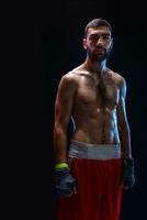 Young male boxer wearing his red boxing shorts and bandage on black background photo