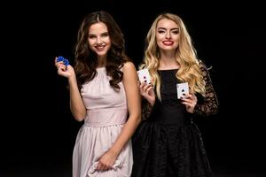 Two Sexy girls brunette and blonde, posing with chips in her hands, poker concept black background photo