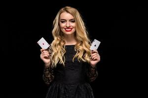 hermosa joven mujer participación dos as de tarjetas en su mano aislado en negro antecedentes foto