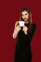 Beautiful caucasian woman in black dress with poker cards gambling in casino photo