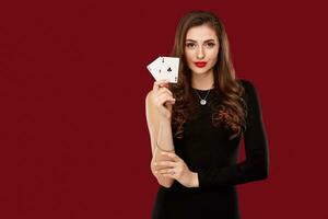 Beautiful caucasian woman in black dress with poker cards gambling in casino photo