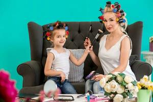 mamá y hija en el estudio en el sofá en el rulos hacer arriba y tener divertido foto