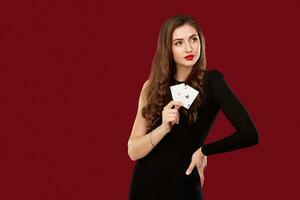 Beautiful caucasian woman in black dress with poker cards gambling in casino photo