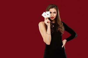 Beautiful caucasian woman in black dress with poker cards gambling in casino photo