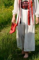 The girl, with her back turned and dressed in Ukrainian national clothes, walks barefoot in the field. photo