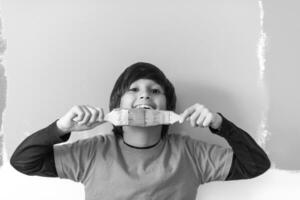 a boy holding paint brushes in front of his face photo