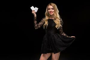 Beautiful young woman holding two ace of cards in her hand isolated on black background photo