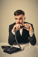 young man dials the phone number while sitting in the office photo