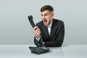 young man dials the phone number while sitting in the office photo