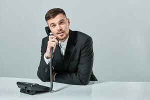 young man dials the phone number while sitting in the office photo