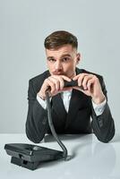 young man dials the phone number while sitting in the office photo