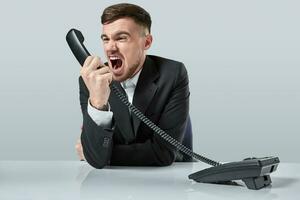 young man dials the phone number while sitting in the office photo