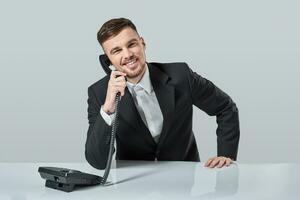 young man dials the phone number while sitting in the office photo