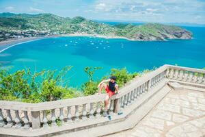 Happy tourist sitting in a viewpoint of a bay. Portrait of tourist man in the view of the bay of San Juan del Sur. Travel and tourism promotion concept photo