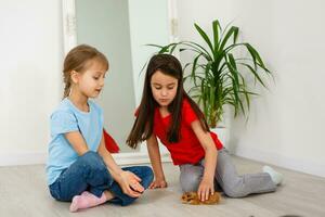 two little girls play with a hamster on the floor at home photo