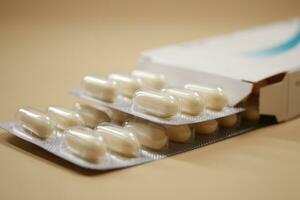 Close up of pills of blister pack and packet on color background photo