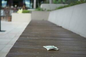 left one dollar cash on park bench photo