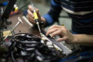 un hombre trabajando en un computadora con un soldadura hierro foto