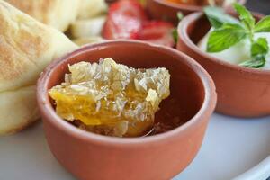 close up of fresh honey with comp in a jar served with bread and strawberry photo