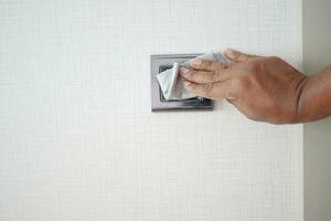 hand with cloth wiping a light switch at the wall photo