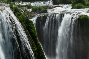 a waterfall in the middle of a forest photo