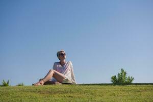 a woman laying on the grass reading a book photo