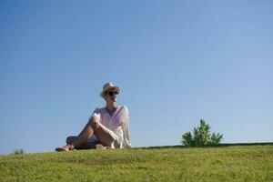 a woman laying on the grass reading a book photo