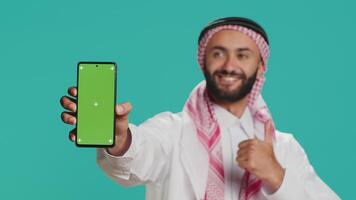 moslim Mens Aan mobiel apparaat met groene scherm thema, zetten vooruit geïsoleerd mockup Chroma sleutel Aan smartphone Scherm. jong Arabisch persoon exposities blanco copyspace sjabloon ontwerp. video