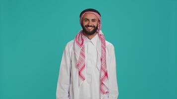 Muslim guy nodding in studio shot, saying yes and expressing his approval. Arab person in traditional clothes showing support about something. Middle eastern man doing positivity and agreement sign. video