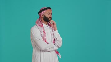 musulman la personne regards contemplatif et en pensant à propos innovant solutions, agissant intéressé et en essayant à trouver répondre. Jeune gars avec foulard étant réfléchi et perplexe sur caméra. video