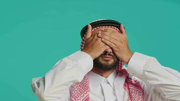 Adult showing three wise monkeys sign on camera, having muslim religious clothing and scarf. Young person covers his eyes, mouth and ears to present important metaphor symbol. video
