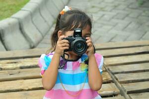 little girl is holding a digital camera photo