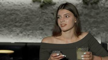 bello giovane donna utilizzando inteligente Telefono mentre potabile a il bar video