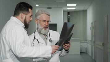 Two male doctors discussing xray scans of a patient at the clinic video