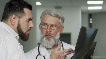 mayor masculino médico y su colega que se discute radiografía escaneos de un paciente video