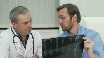 Two mature male doctors discussing MRI scan of the patient video