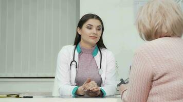 jovem fêmea médico ouvindo para dela Senior paciente durante médico compromisso video