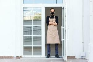 male cafe owner in apron and protective mask photo